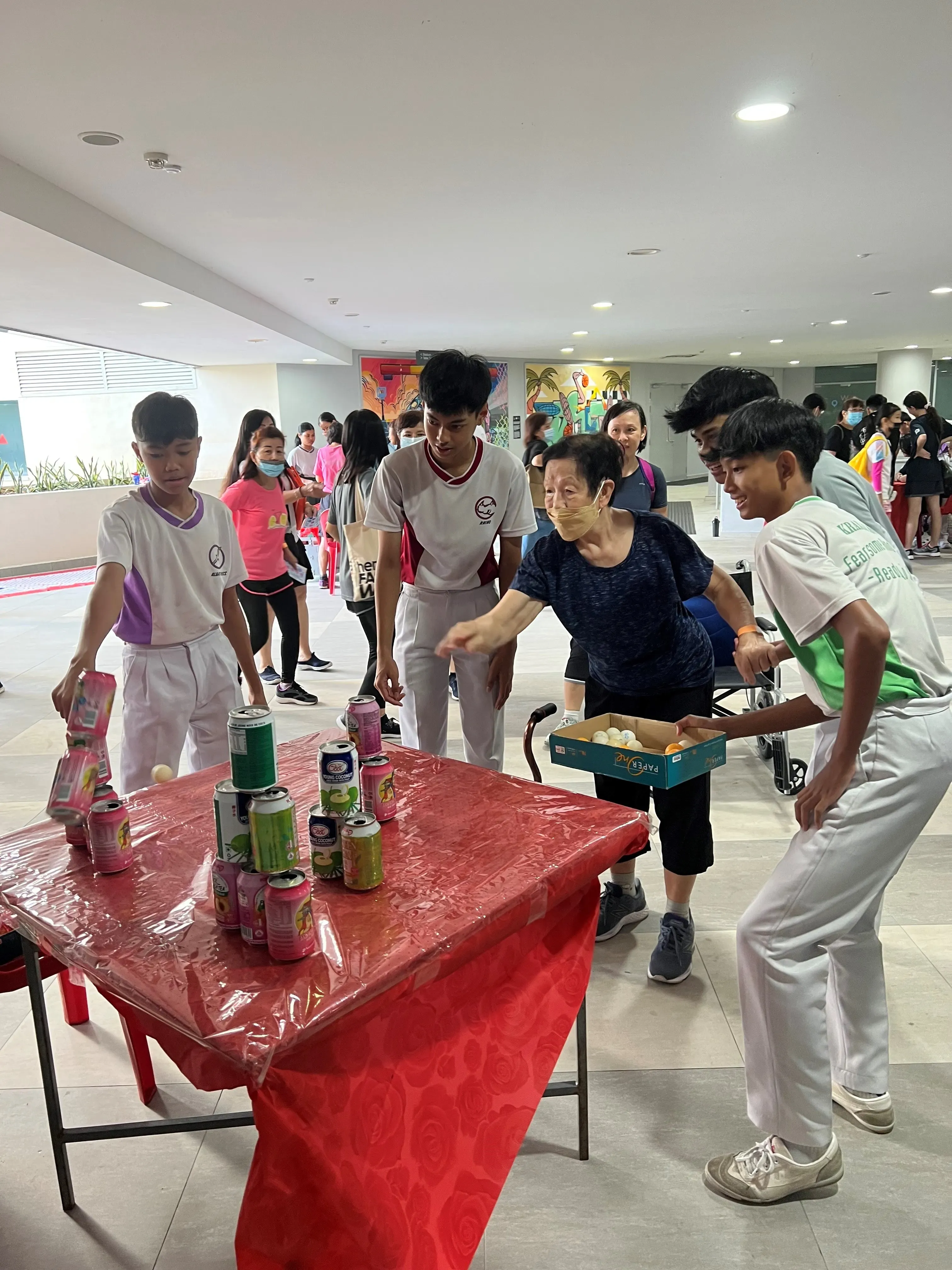 Participants are knocking down cans with ping pong balls, testing their hand-eye coordination and dexterity.