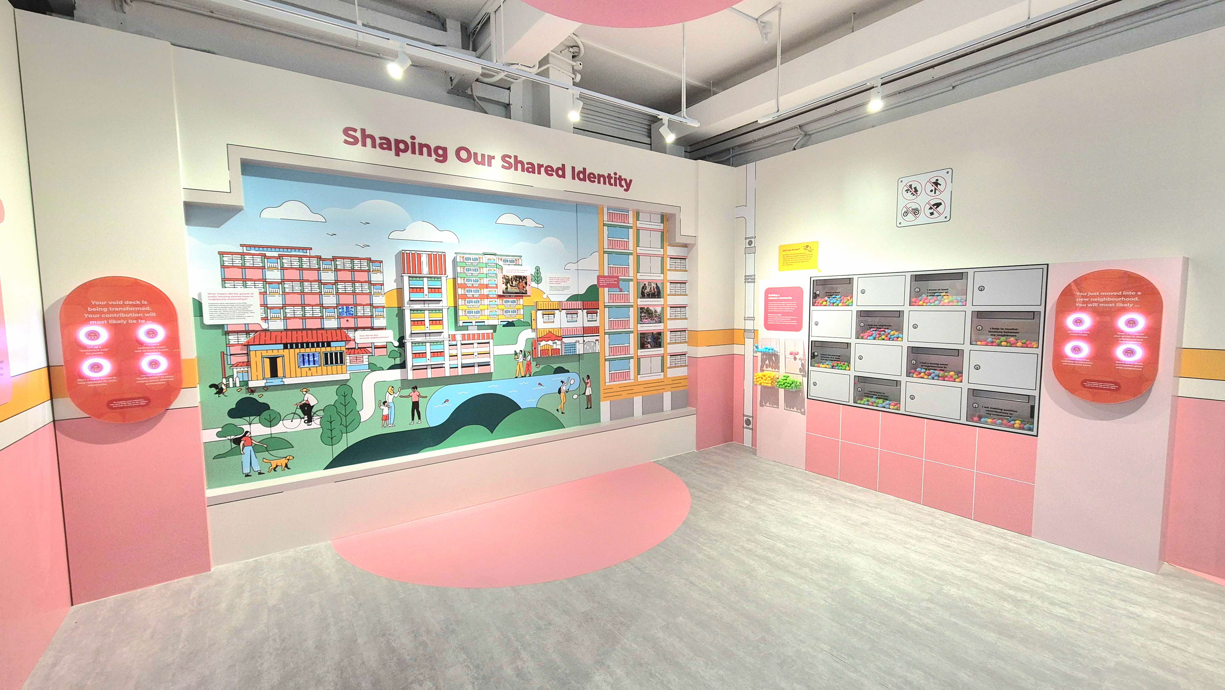A pink-themed museum exhibit titled "Shaping Our Shared Identity" with a colorful neighborhood mural and interactive panels.