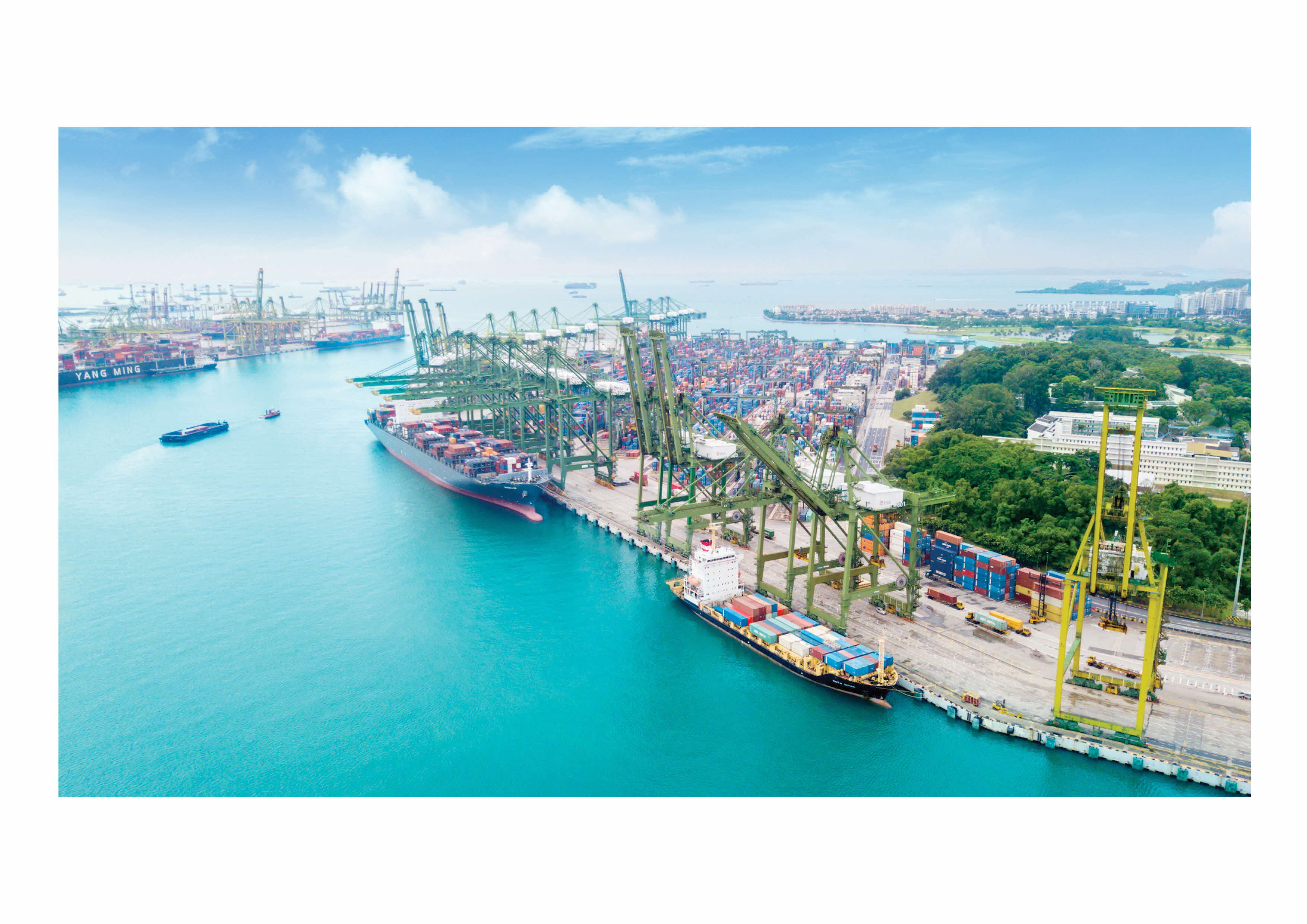 Aerial view of a busy container port with large cranes, colorful stacked containers, and cargo ships on blue water.