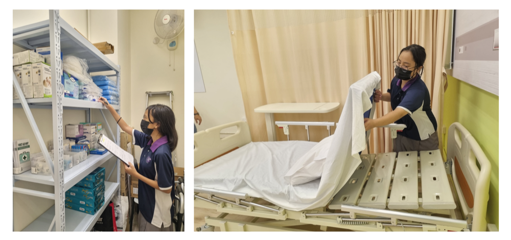 Two masked healthcare workers, one checking medical supply shelves and one making a hospital bed with white sheets.