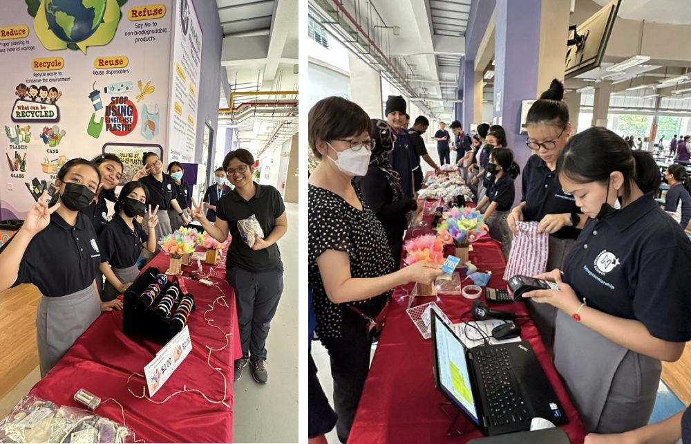Students in black uniforms run a school market booth selling handmade items, with a recycling awareness poster behind them.