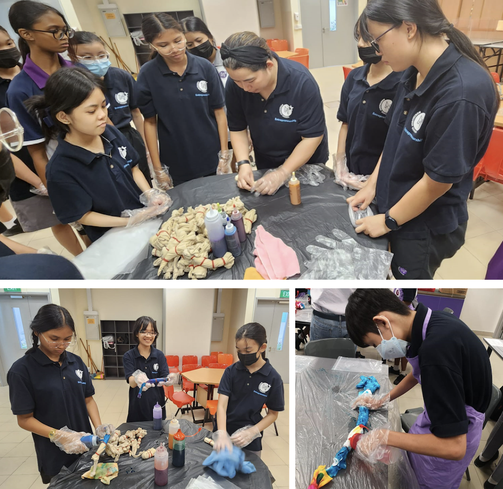 Students in navy uniforms apply colorful dye to twisted fabric during a tie-dye activity indoors.