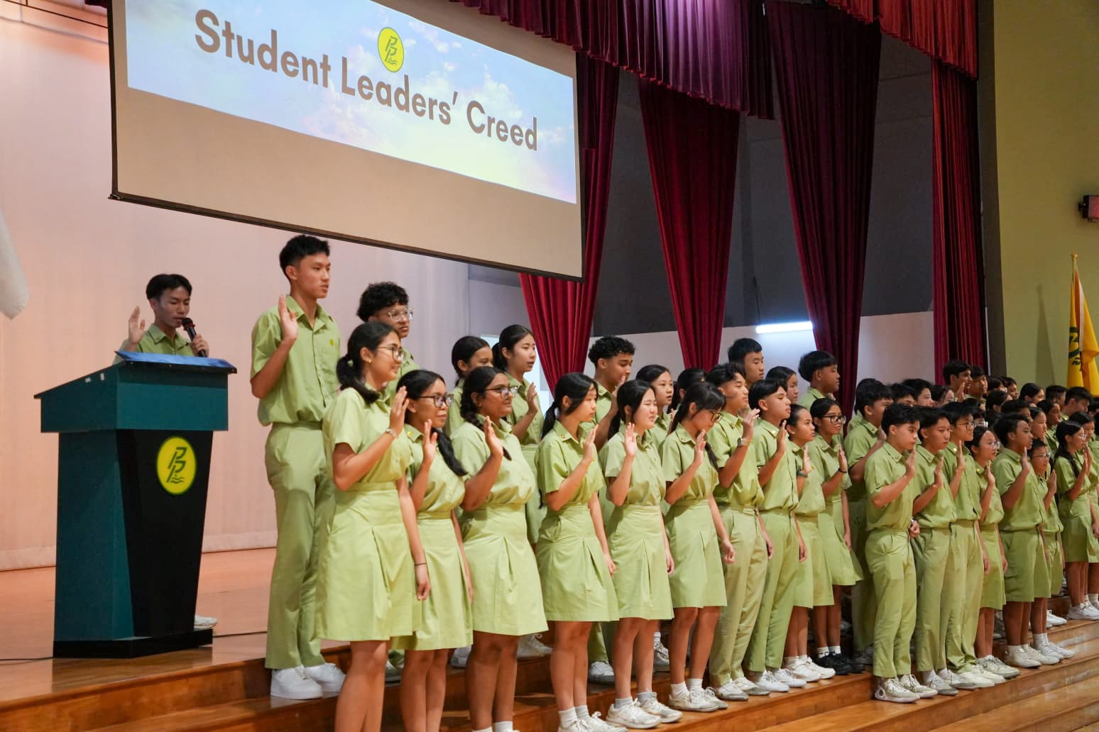 Students standing on stage reading a pledge.
