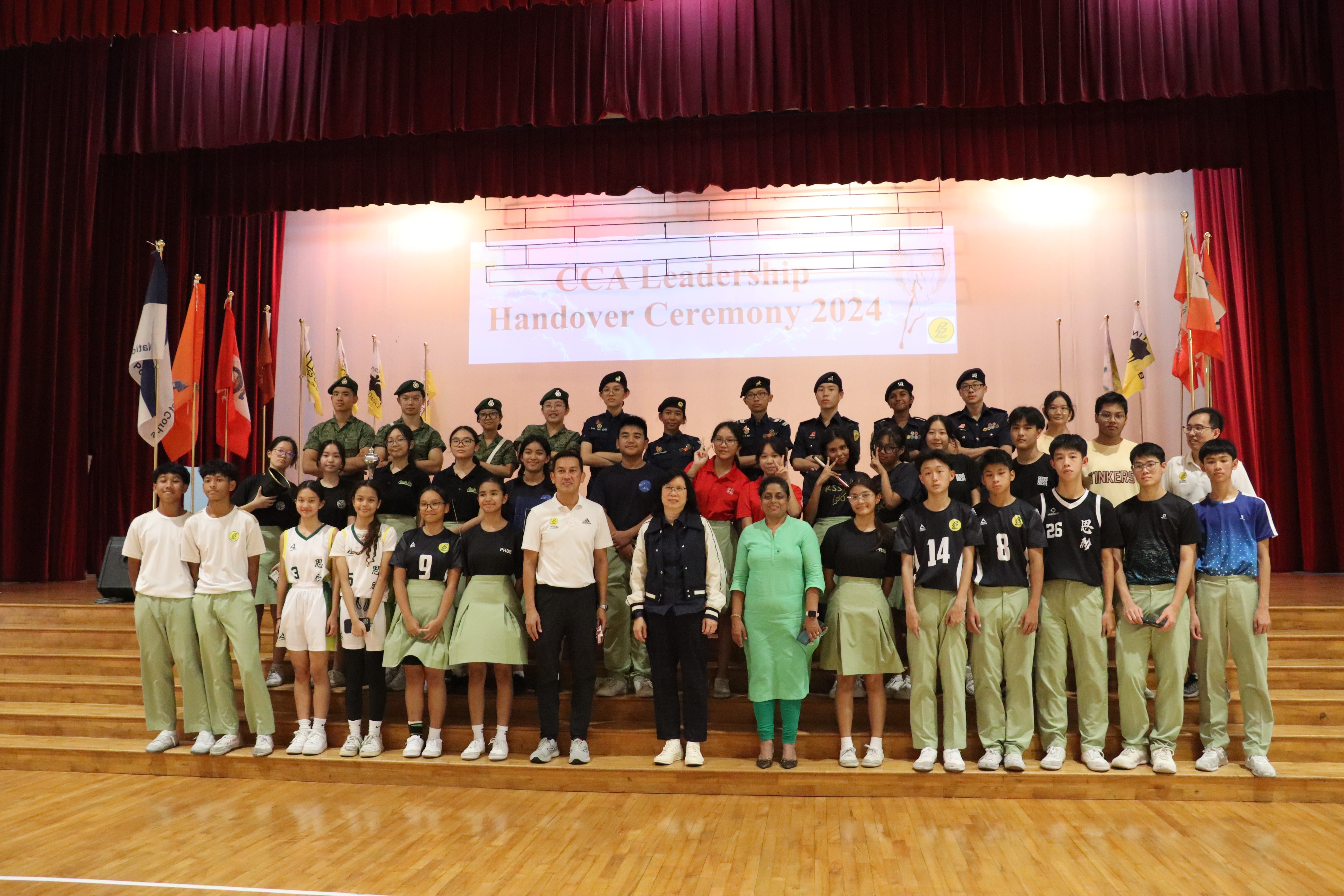 Group photo of students and staff at the stage full of flags.