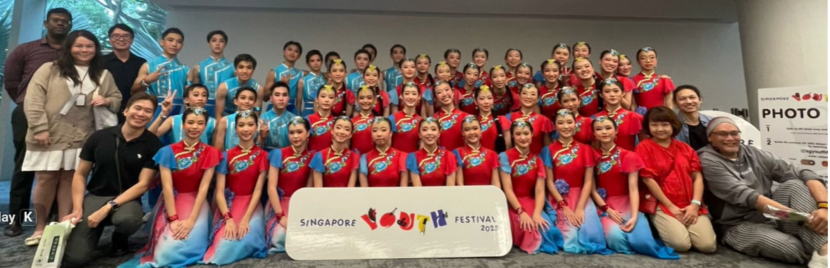 Large group of performers in red and blue traditional Chinese costumes posing at Singapore Youth Festival 2025.