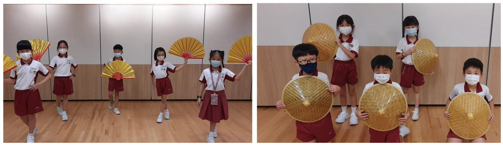 Young children in school uniforms and masks pose with gold fans and large woven bamboo hats indoors.