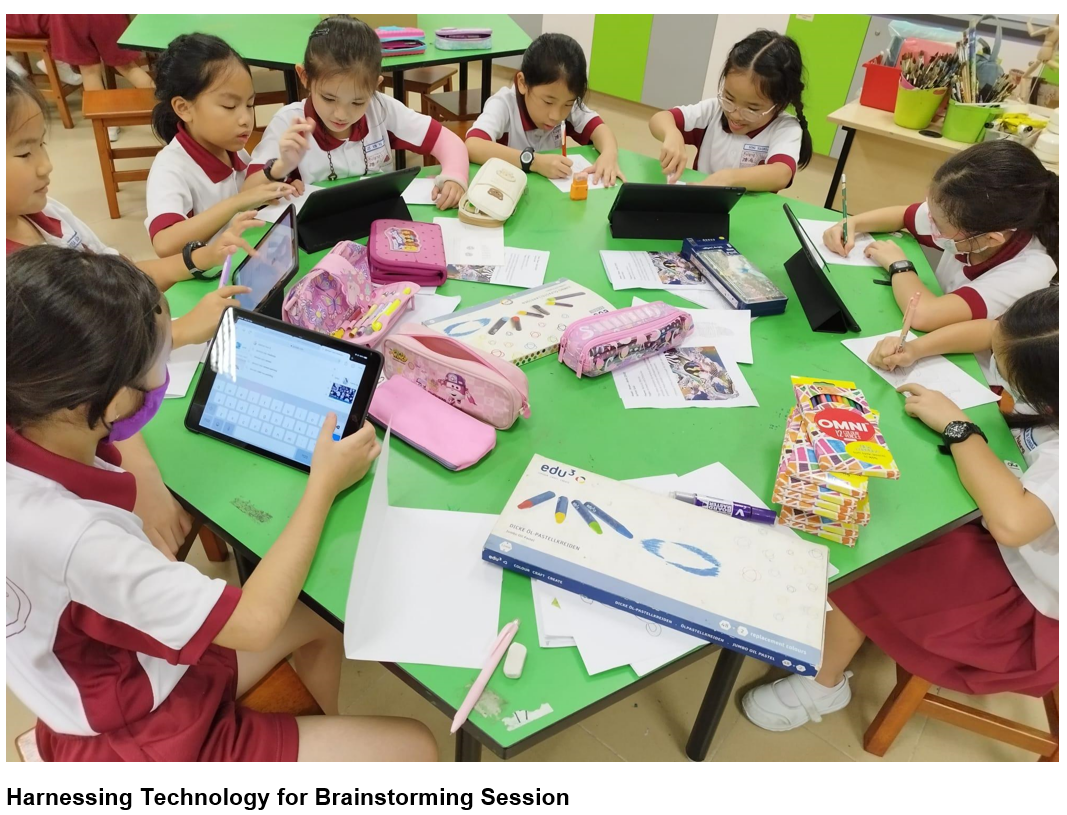 Several young students in school uniforms sit around a green table using tablets and writing on papers with pencil cases and crayons.