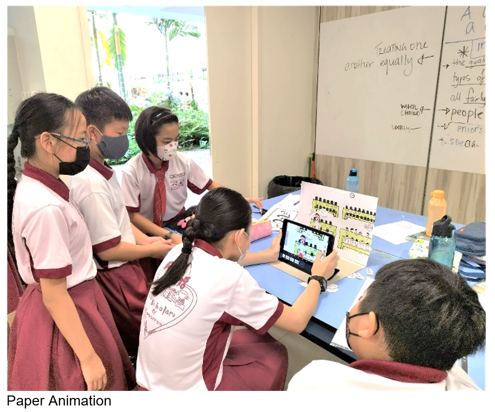 Five masked school children in uniforms gather around a tablet displaying an animation, with a whiteboard behind them.