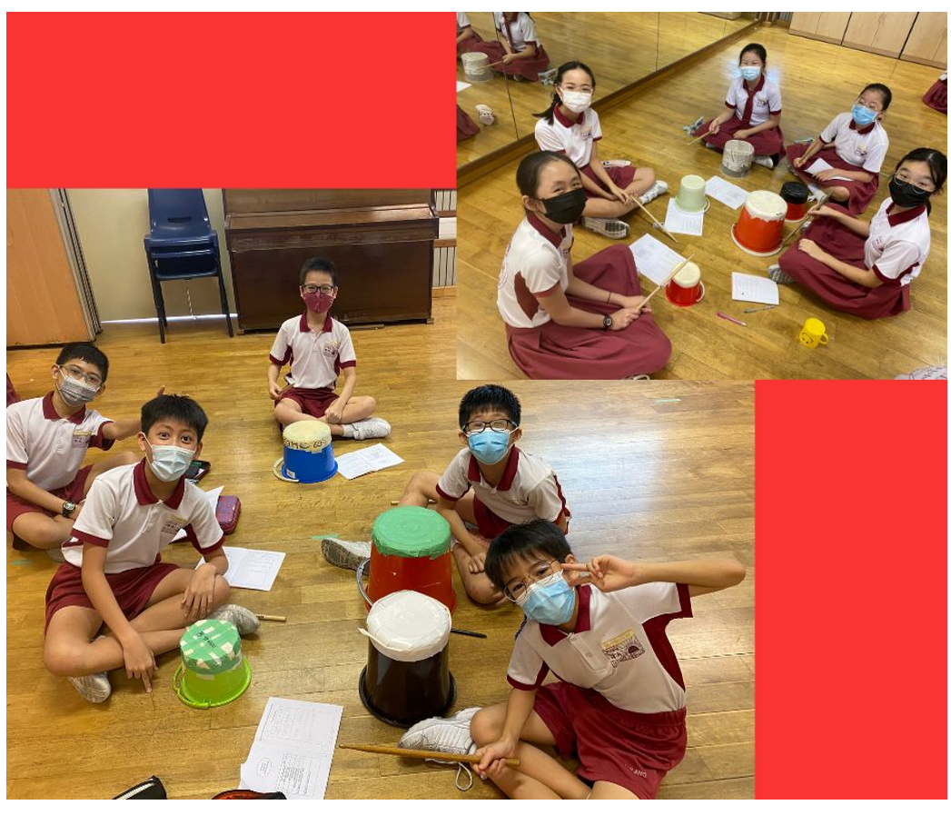 Students in school uniforms and masks sit on a floor playing homemade drums made from buckets and containers.