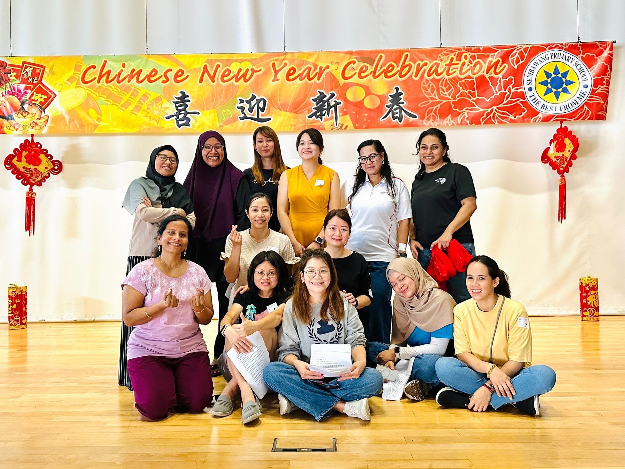Group of women posing in front of a Chinese New Year Celebration banner at Sembawang Primary School.