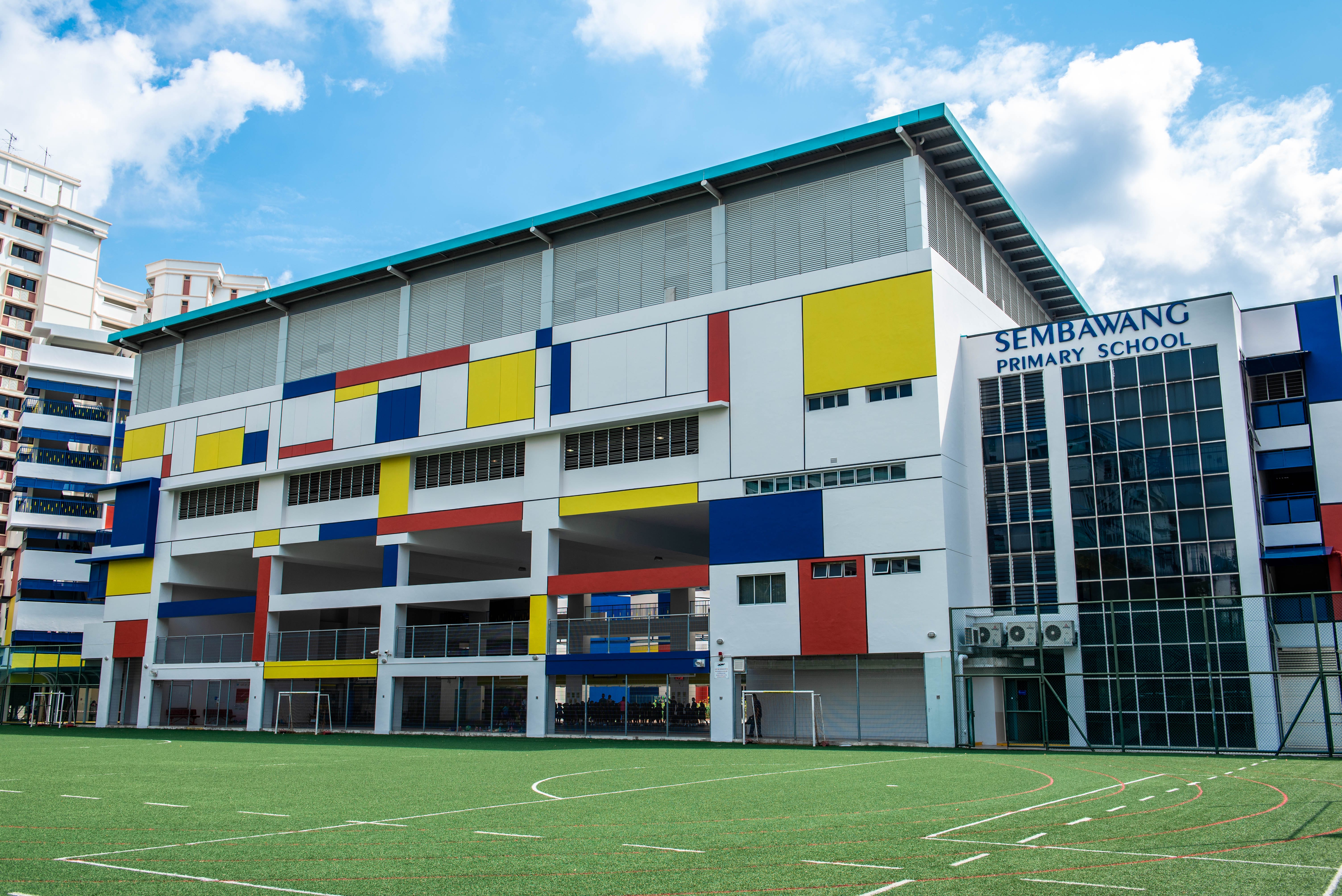 Sembawang Primary School building with colorful red, yellow, and blue panels, beside a green sports field.