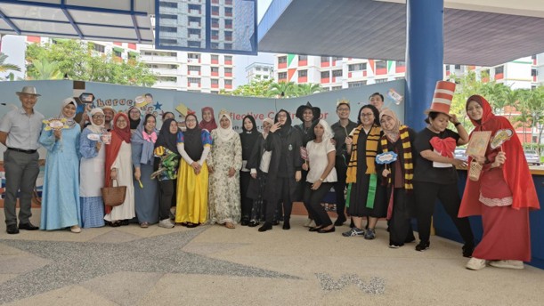 A large group of teachers in diverse storybook costumes — including Snow White, Harry Potter characters, Little Red Riding Hood, and Cat in the Hat — pose together outdoors in front of a "Characters Alive" banner.