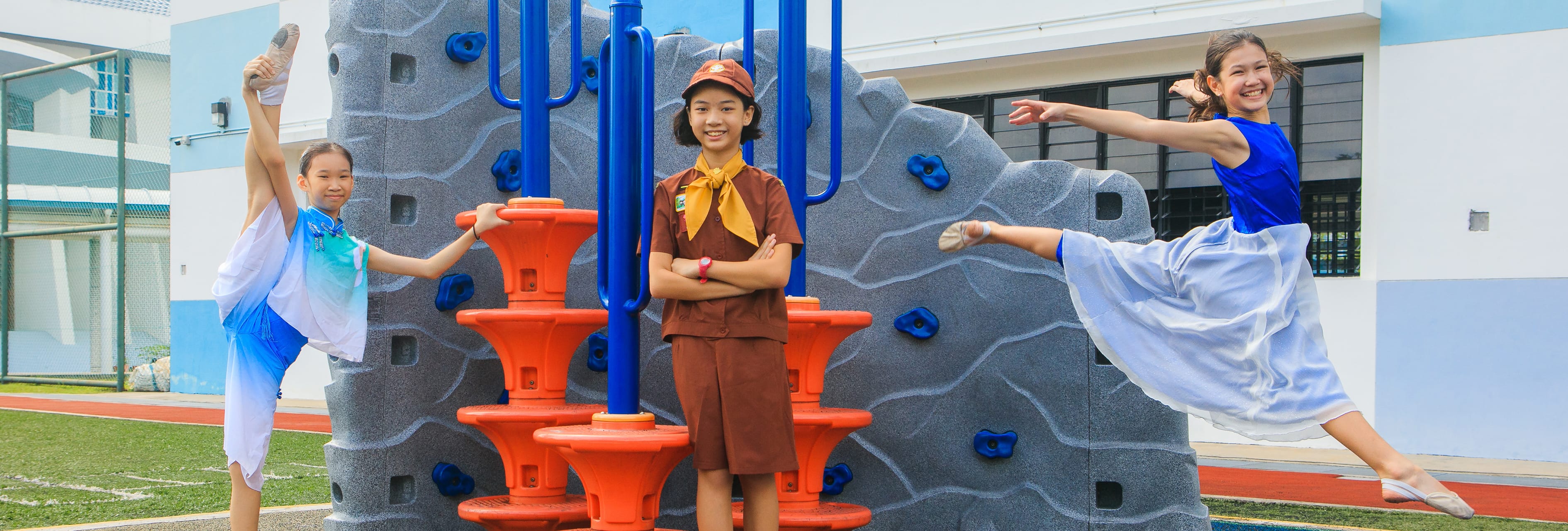 Three children pose on playground climbing wall; two do high kicks in dance outfits, one stands in uniform.