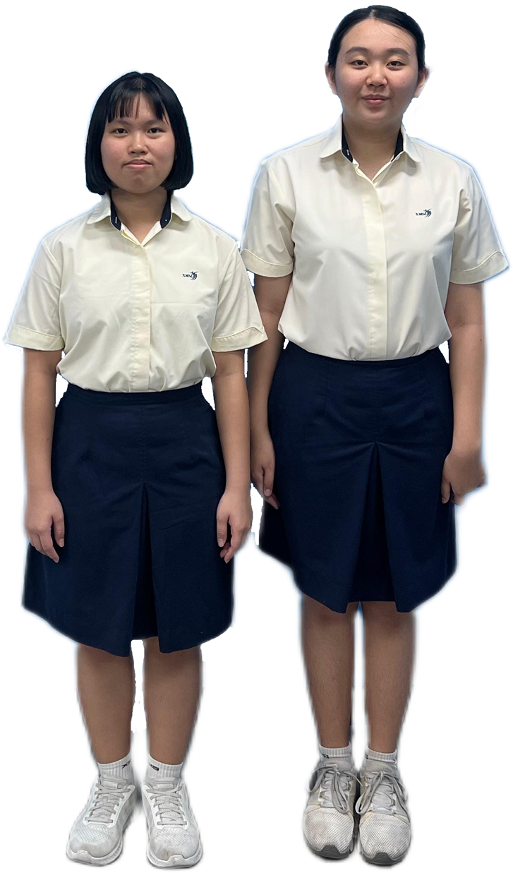 Two young women in matching school uniforms of cream shirts, navy skirts, and white sneakers stand side by side.