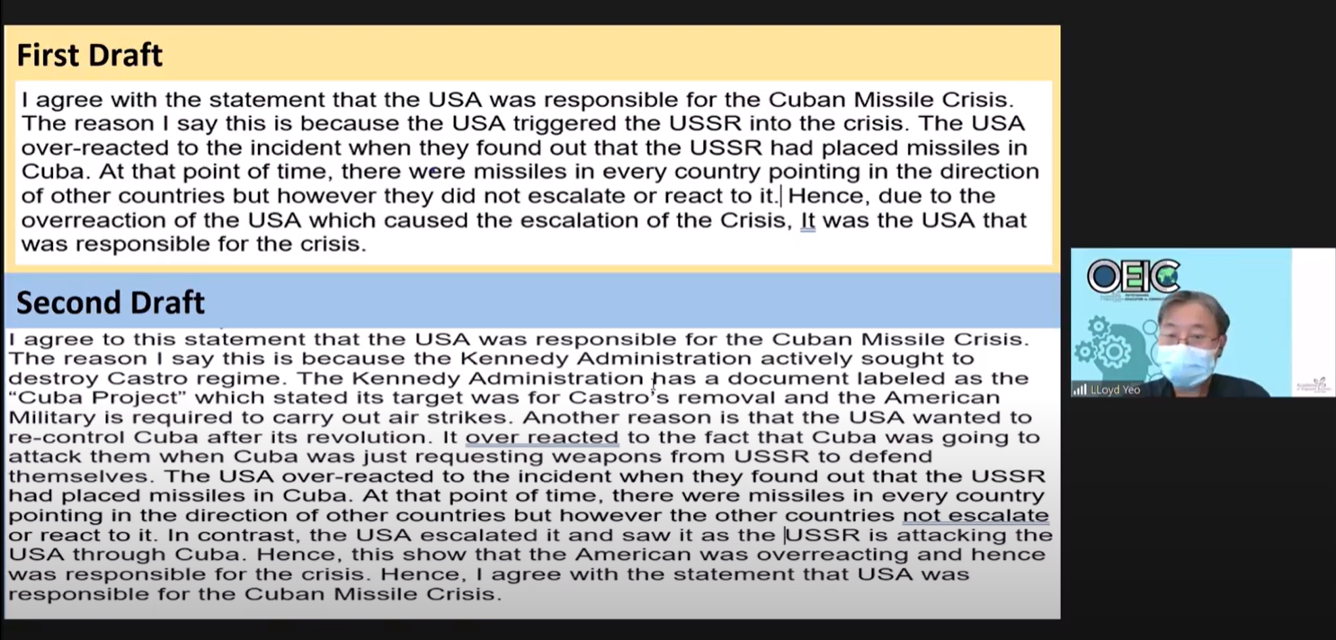 Slide showing First Draft and Second Draft essays about USA's responsibility for the Cuban Missile Crisis, with a masked presenter visible.