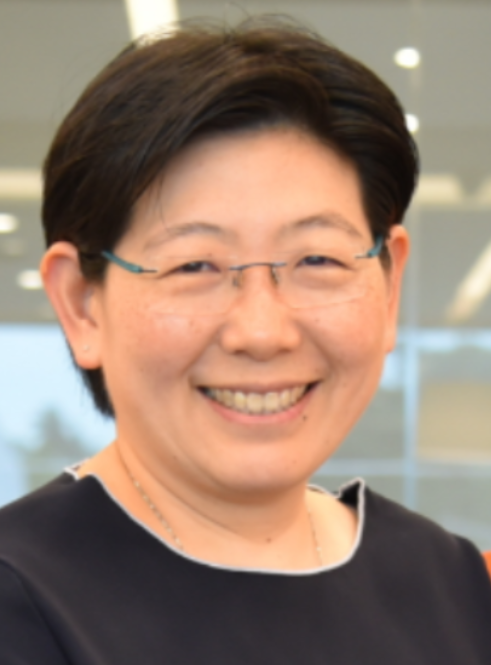 A smiling woman with short dark hair, thin-framed glasses, and a dark top with a necklace.