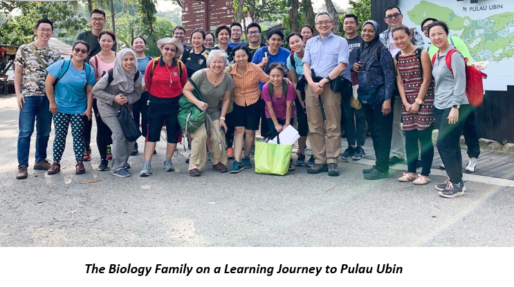 A large group of people posing together outdoors near a Pulau Ubin sign on a learning journey.
