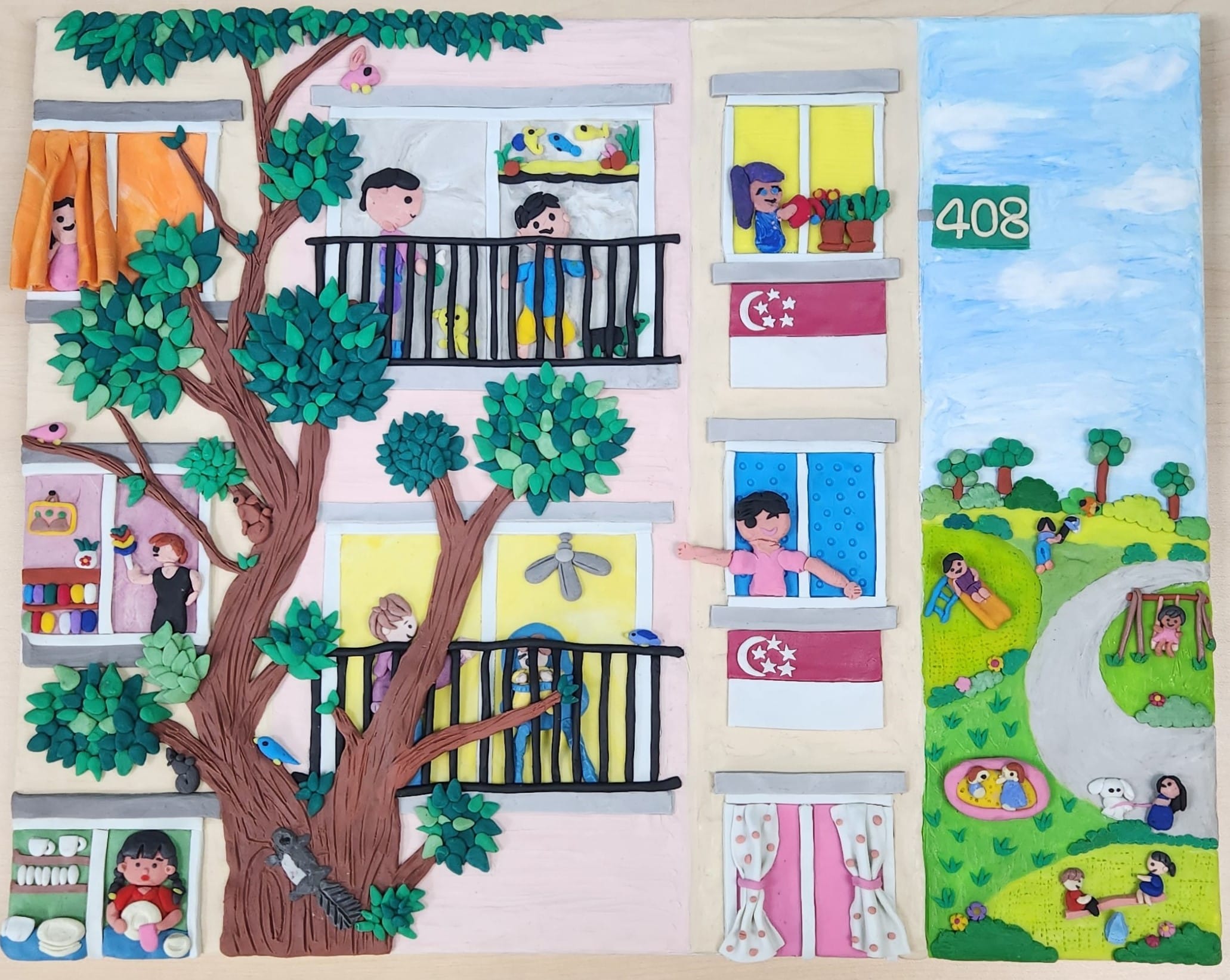 A colourful clay artwork depicting everyday life in a Singapore heartland neighbourhood. Residents are shown interacting from HDB flats, children play in a nearby park, and lush trees filled with birds and squirrels surround the estate. Singapore flags hang from several windows, while details such as a playground, walking paths, pets, and family activities create a warm and vibrant scene that celebrates community, nature, and neighbourhood life.