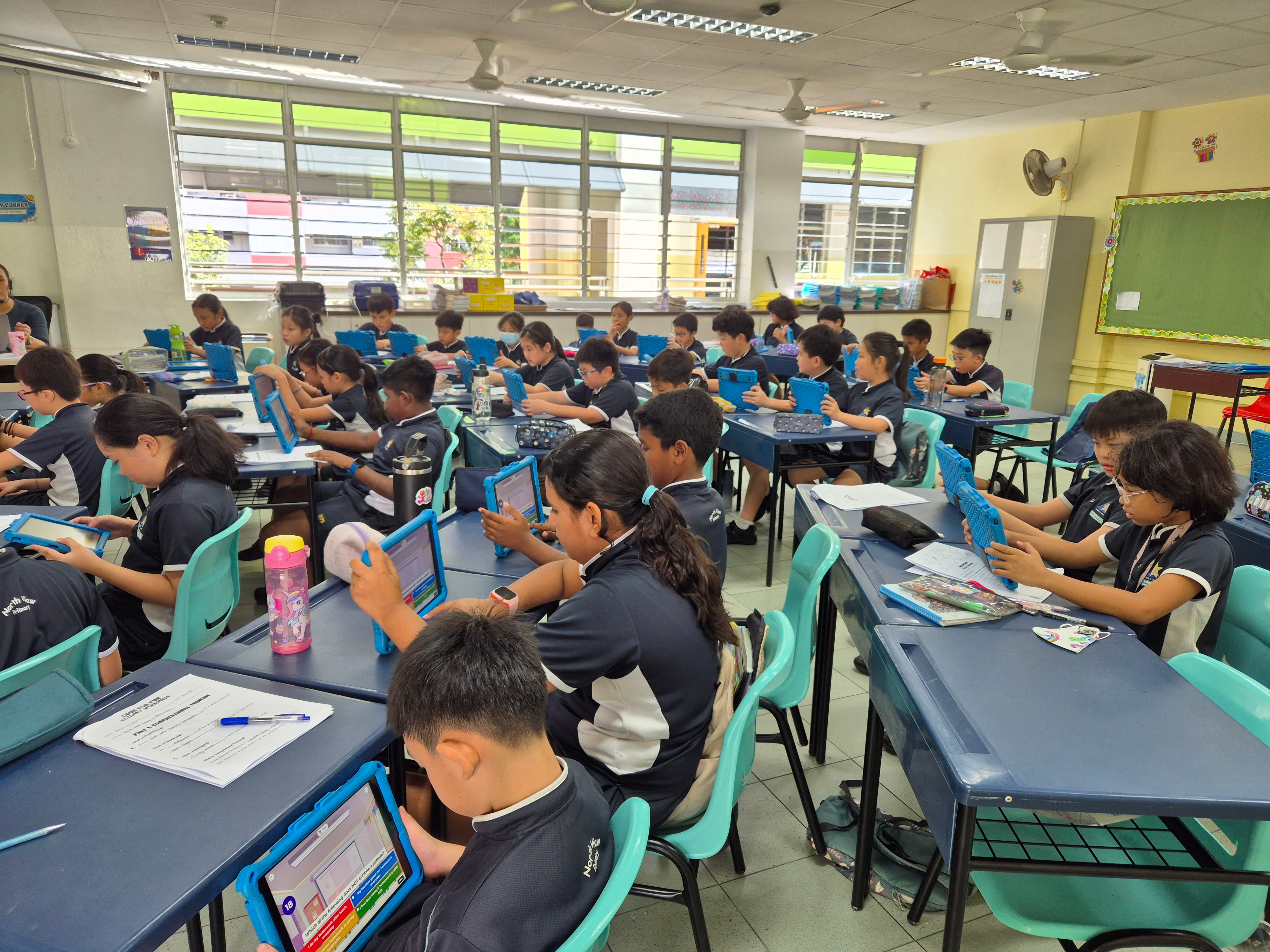 An entire class uses iPads during a lesson, with students actively engaged in digital learning while the teacher facilitates the activity.