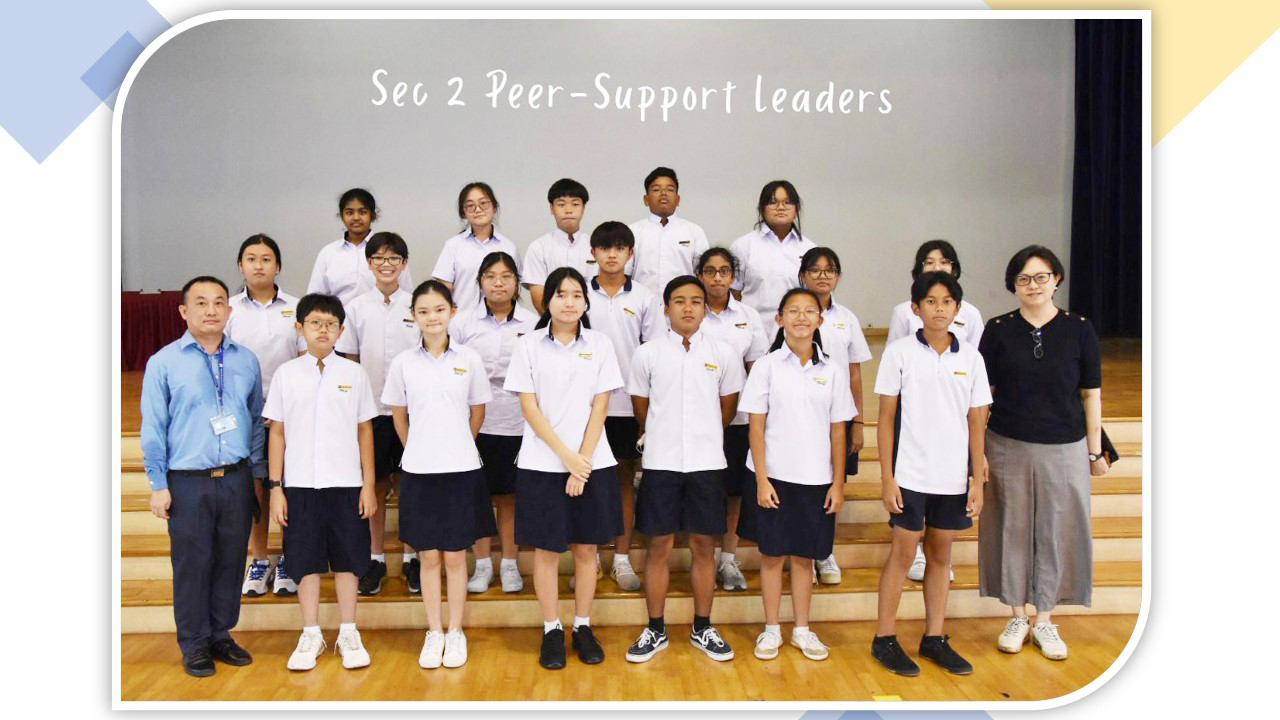 Group photo of Sec 2 Peer-Support Leaders in school uniforms with two adult teachers in a hall.