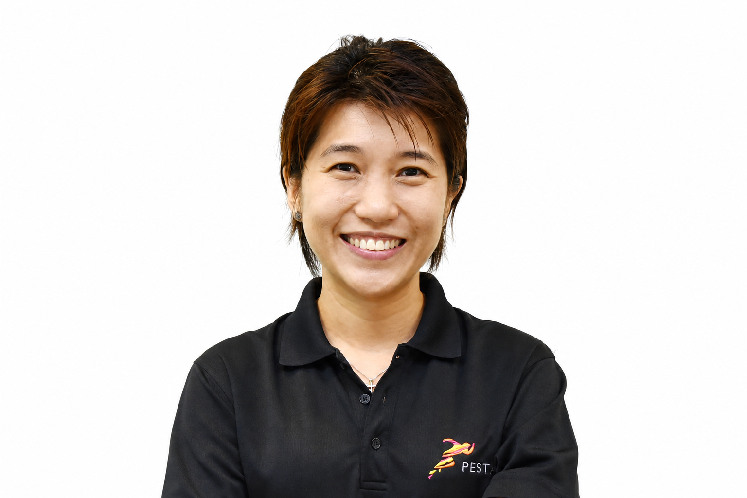 A smiling woman with short brown hair wearing a black polo shirt with a pest control company logo.