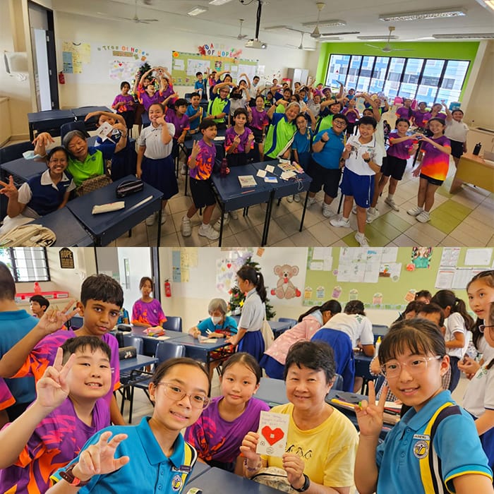A large group of school children and elderly adults pose cheerfully in a colorful classroom setting.