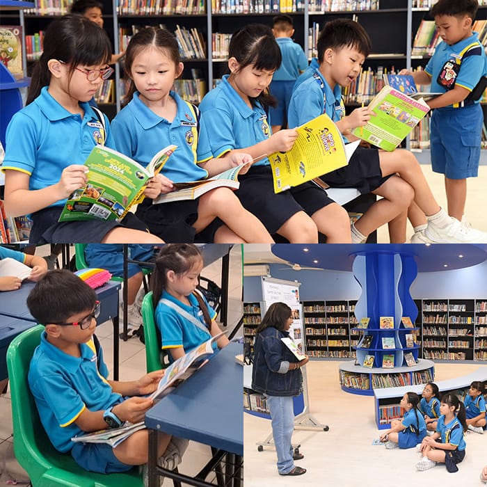 Children in blue uniforms read books in a school library as a teacher addresses students sitting on the floor.