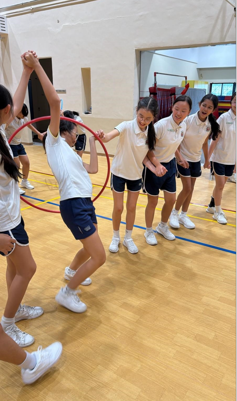 Students passing a hulla hoop around their bodies