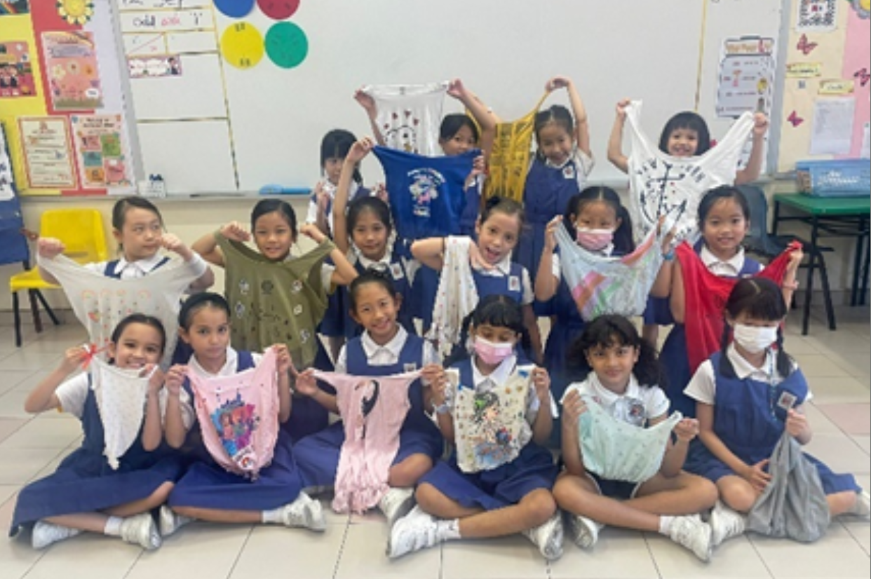 Students posing with recycled bags made from t-shirts