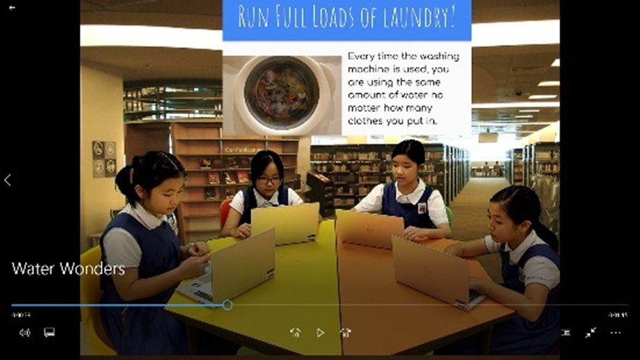 Four young students sit at a table with laptops in a library, with a slide about running full laundry loads visible.