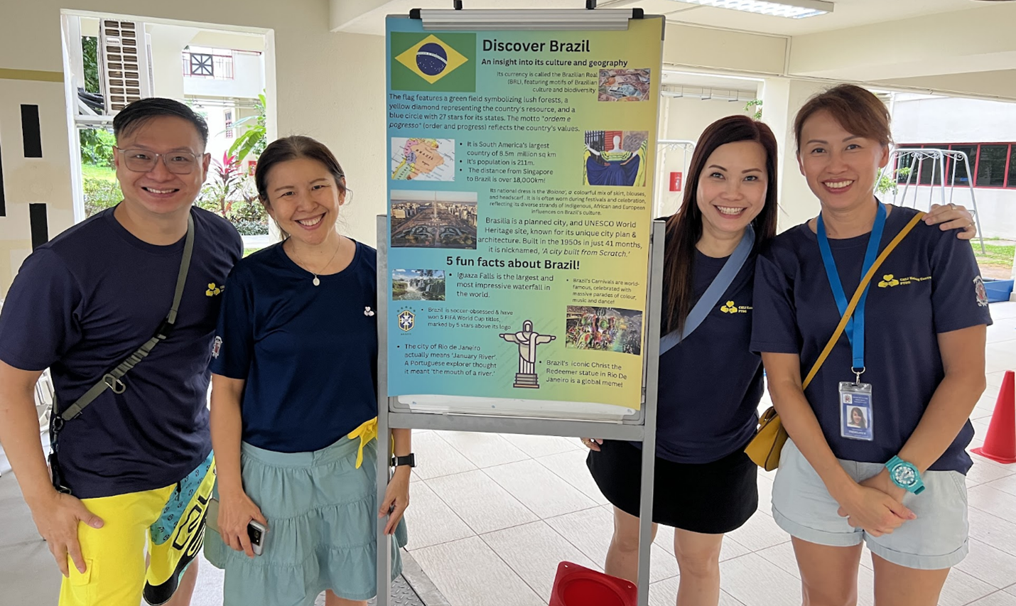 Four smiling people stand beside a colorful Discover Brazil informational poster outdoors.