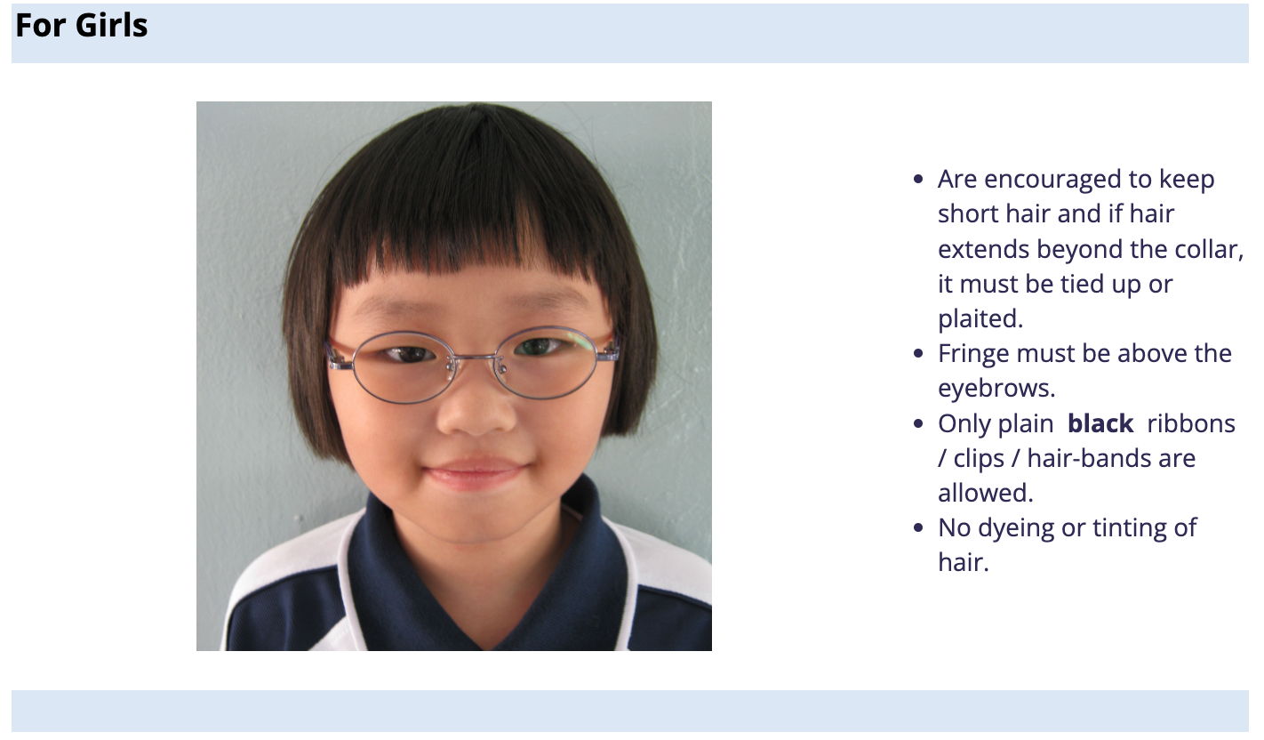 A young girl with a short bob haircut, fringe above eyebrows, oval glasses, wearing a school uniform.