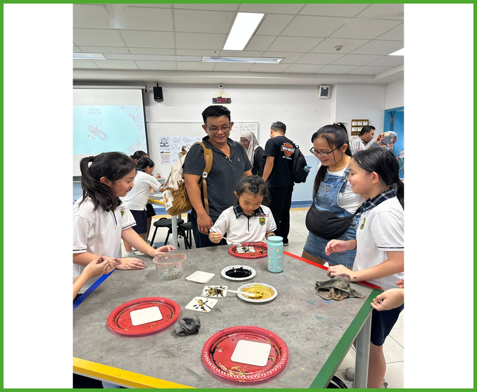 Children and adults gather around a table with trays, bowls, and art materials during a classroom activity.