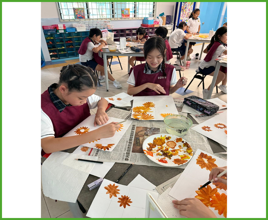 Students in maroon uniforms paint orange flowers on white paper at tables covered with newspaper in an art classroom.