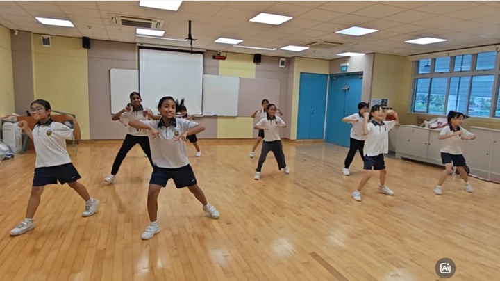 9 modern dance members in school physical activity attire practice their dance moves in an air-conditioned room.