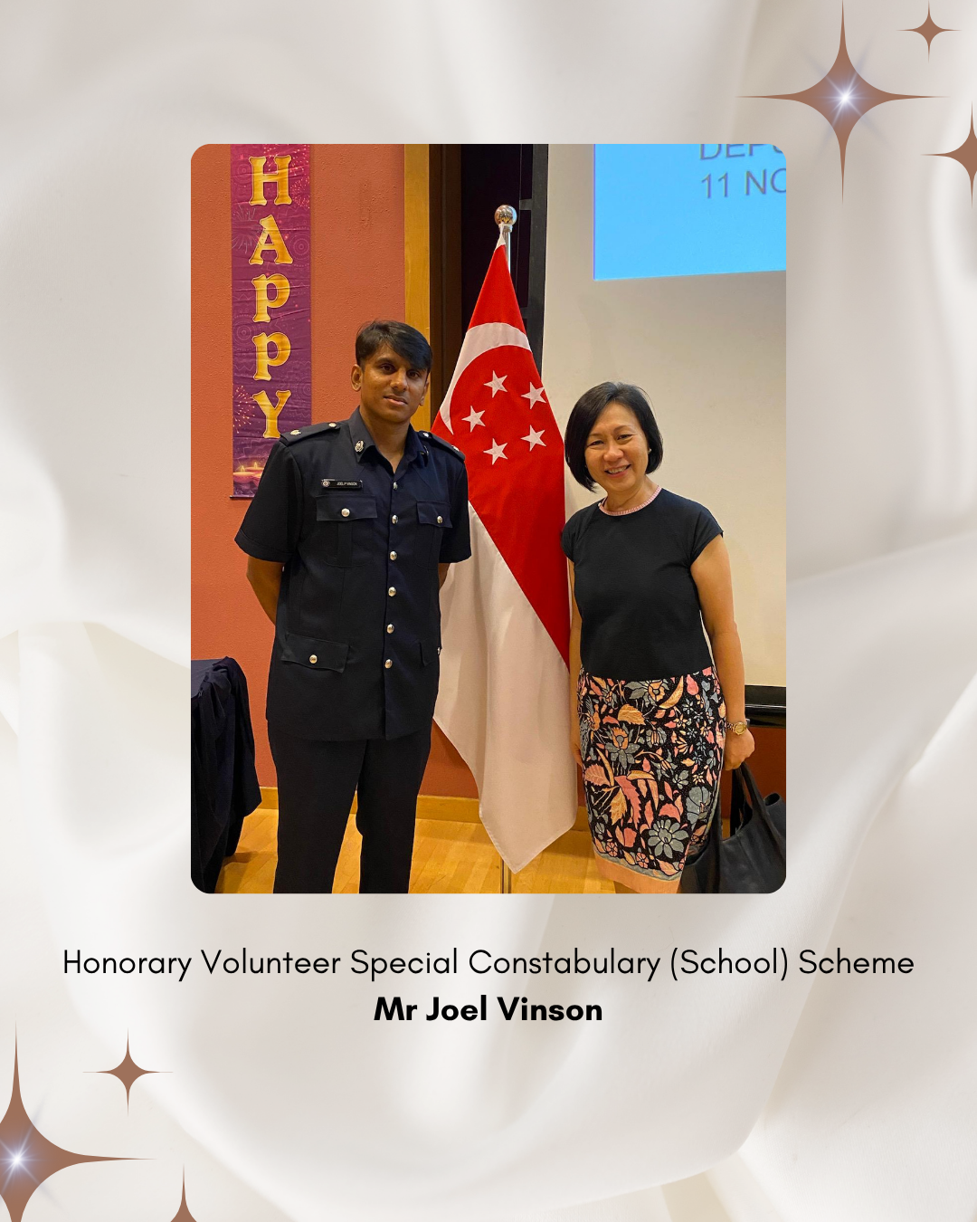 A school representative stands beside a volunteer police officer in uniform during recognition of contributions to school safety programmes.