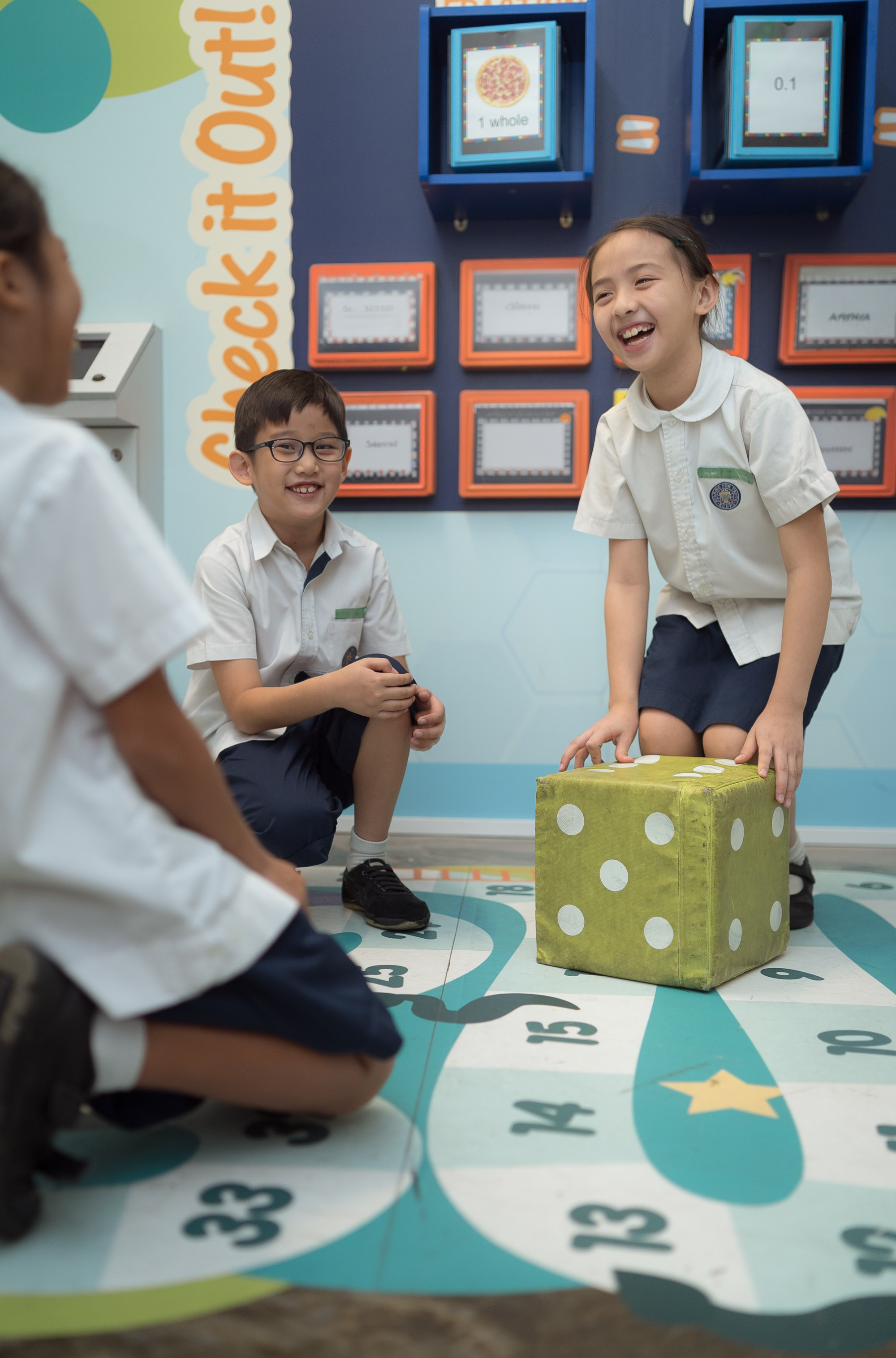 3 pupils playing dice together at the Maths corner.