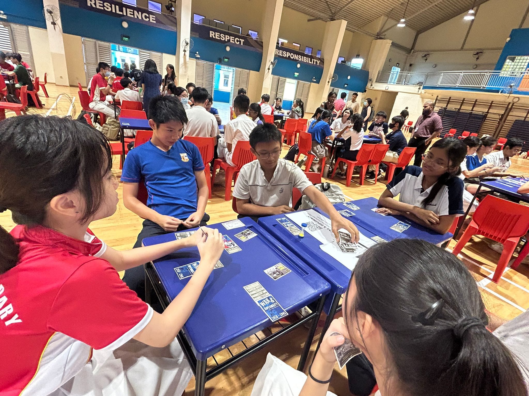 A group of students sitting on a chair in circles and playing card games