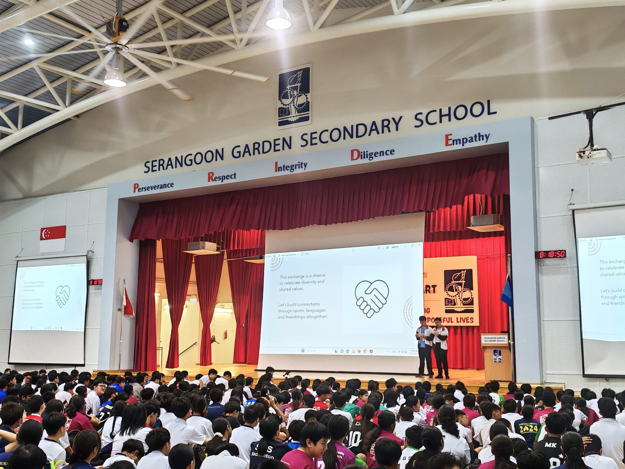 Students fill a school hall during an assembly at Serangoon Garden Secondary School, with a presentation on stage.