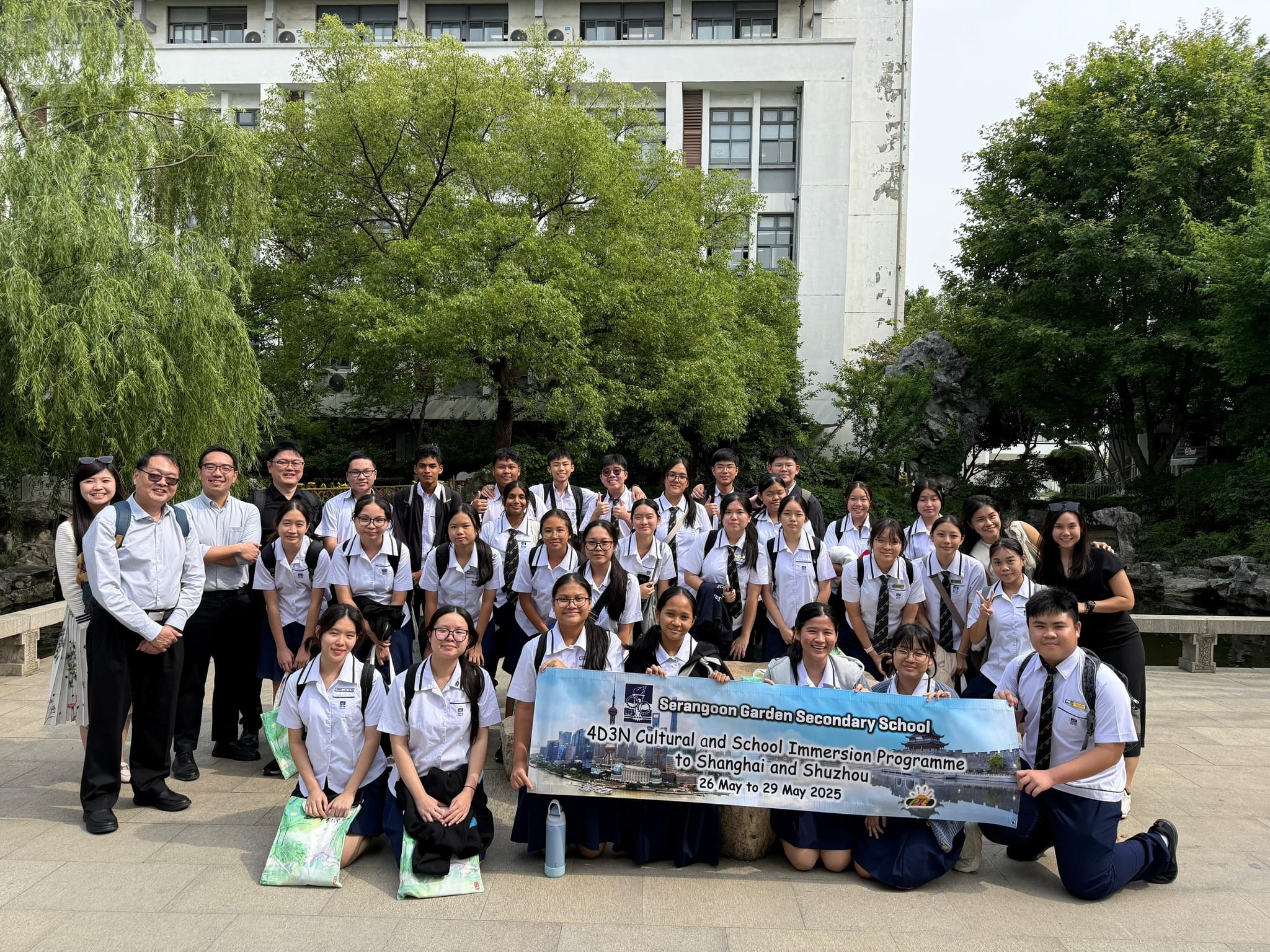 Students and teachers from Serangoon Garden Secondary School pose outdoors holding a banner for their Shanghai and Shuzhou trip.