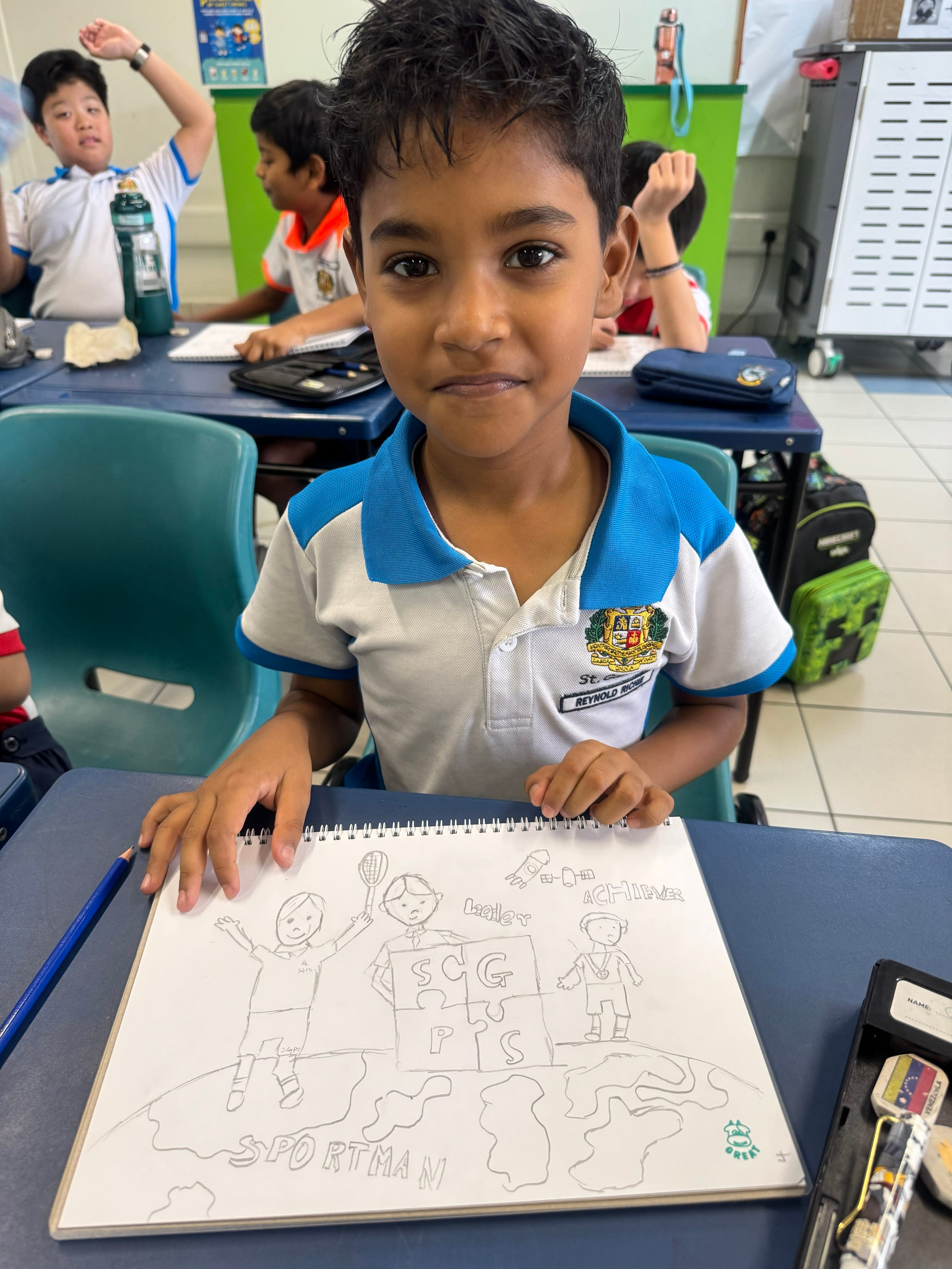Student in blue-collared uniform at desk, holding sketchbook with pencil drawing; classmates behind.