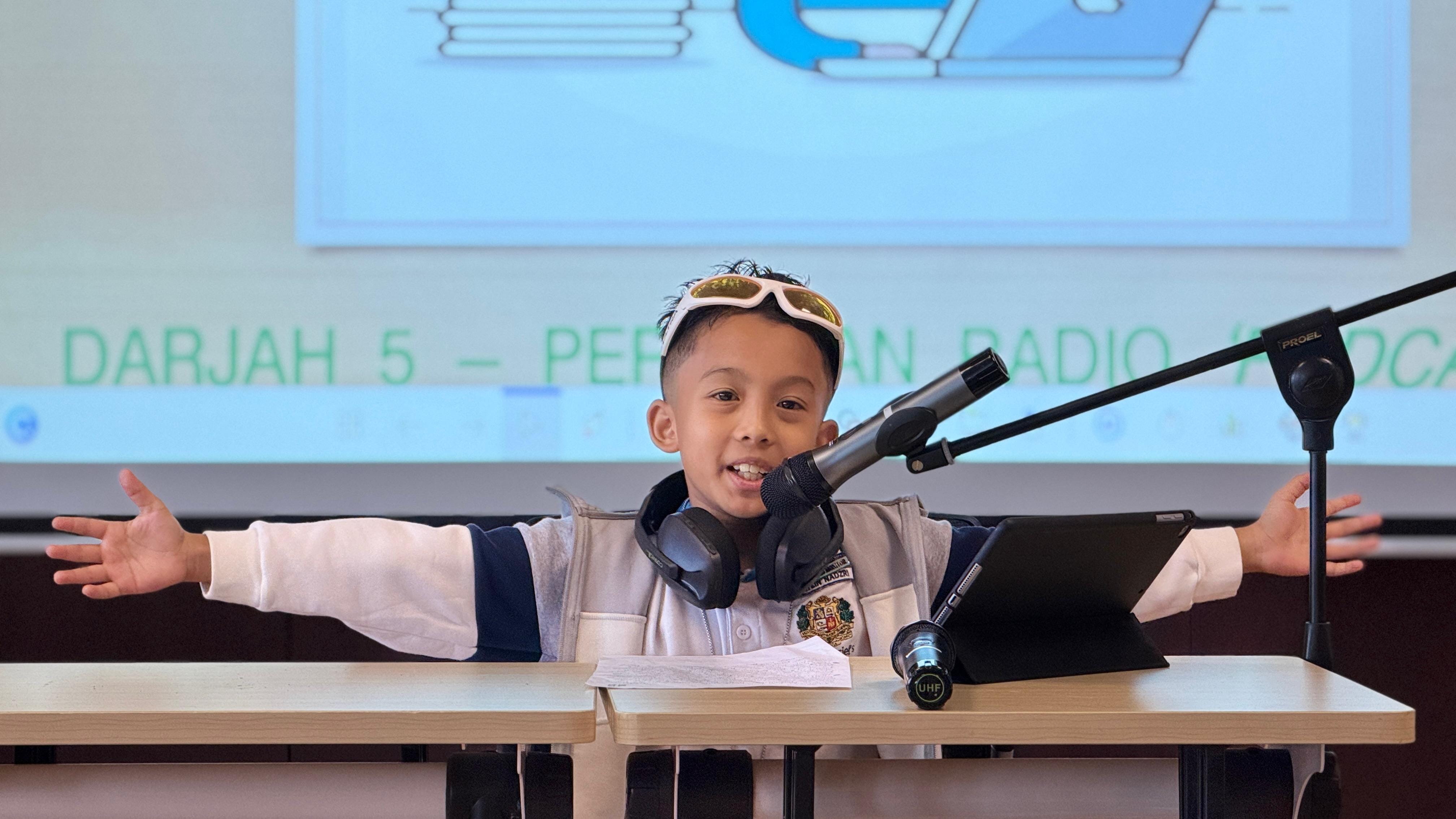 A student dressed up as a DJ wearing a jacket and yellow sunglasses mimicking a radio DJ