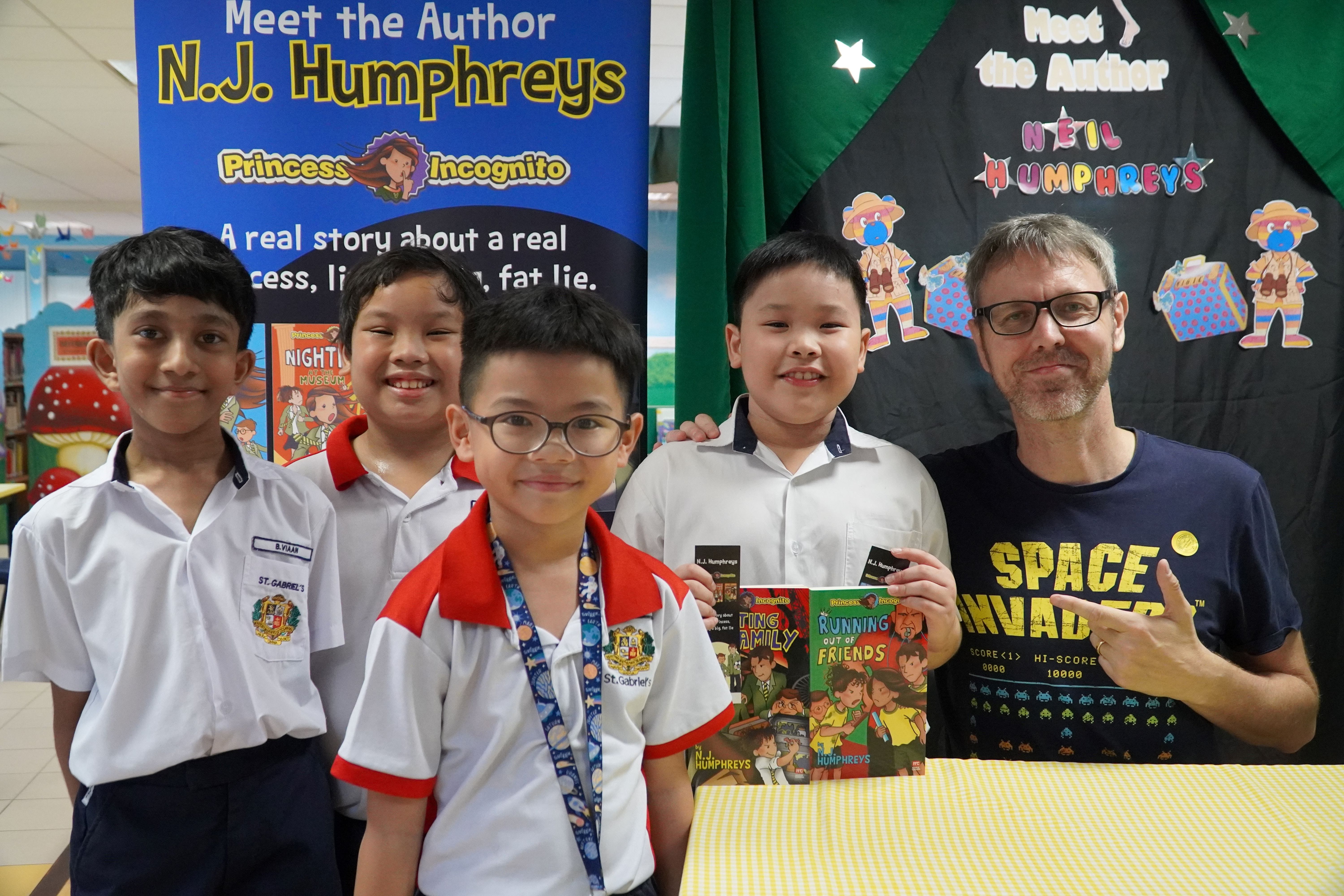 Four students taking a photo with a book author