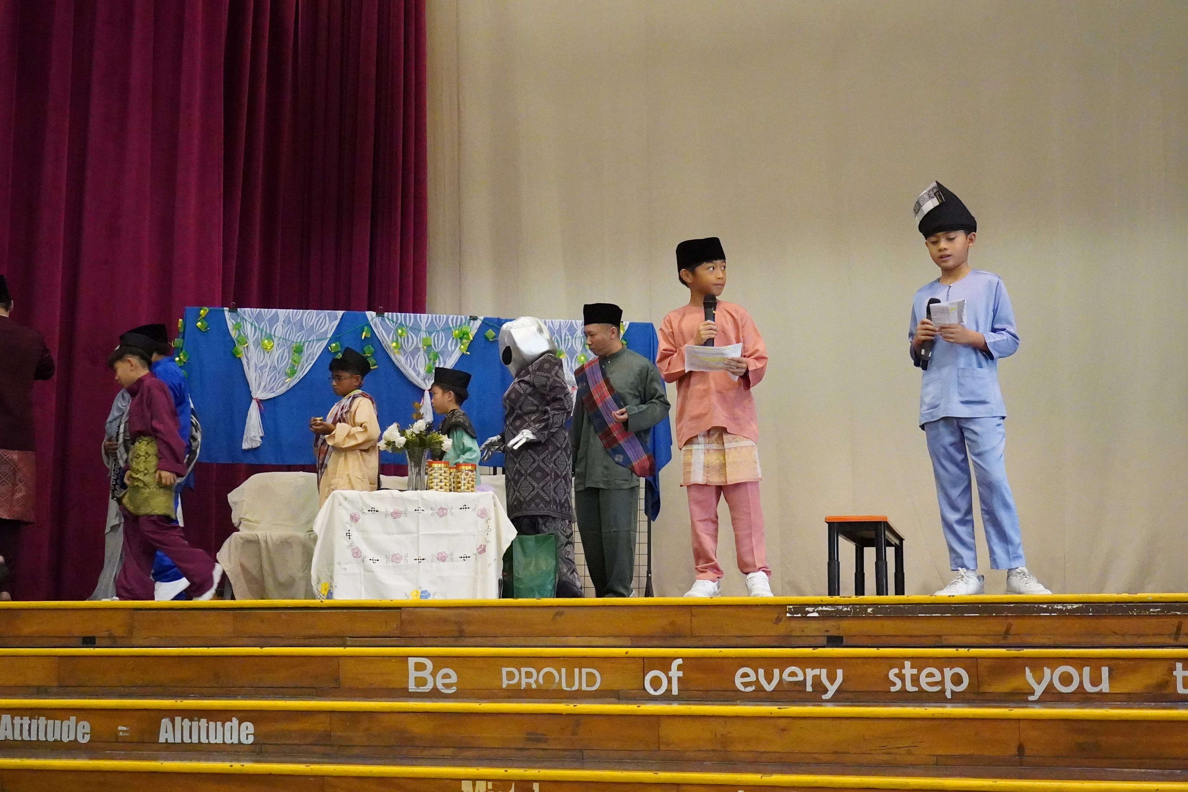 Two students emceeing while students and teachers are taking part in the Hari Raya activity in the school hall