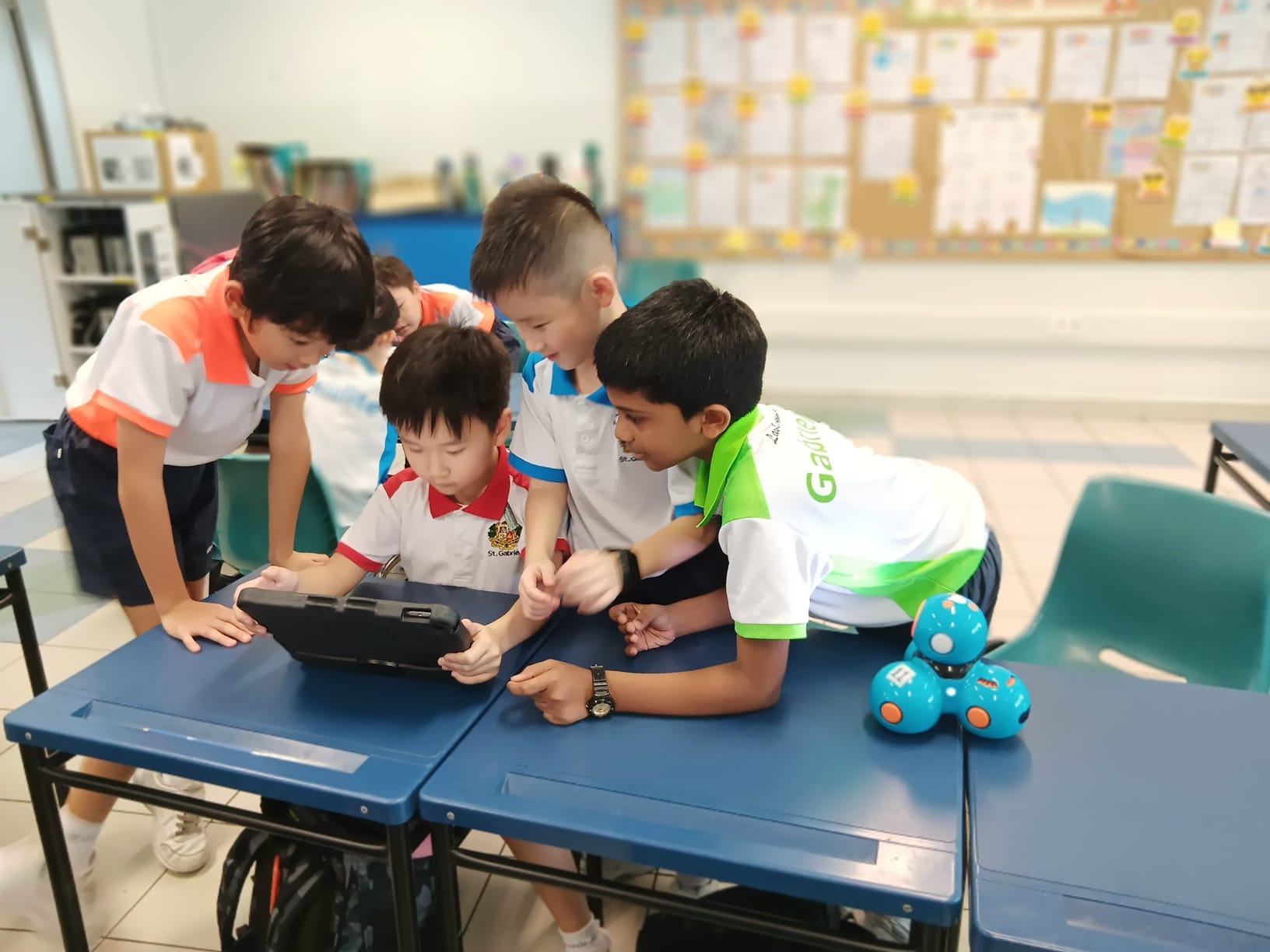 Four students working on a robot on the table together with an iPad