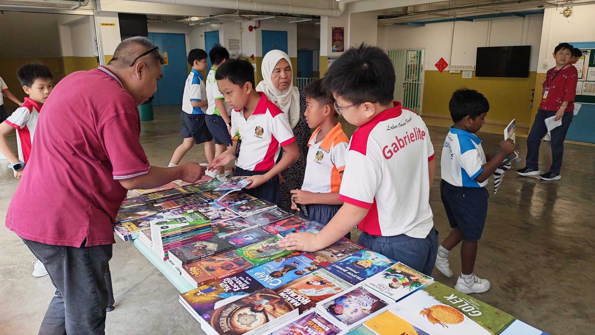 A student asking the seller what the book is about with students and teachers standing around