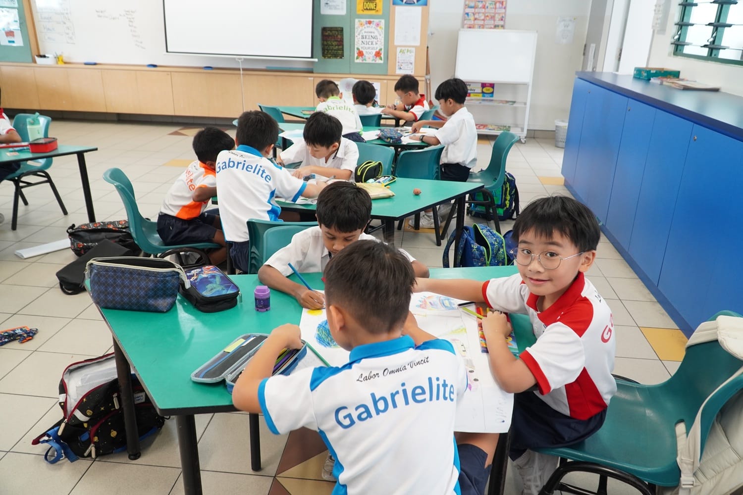 Students actively drawing on their tables and sitting on their chair