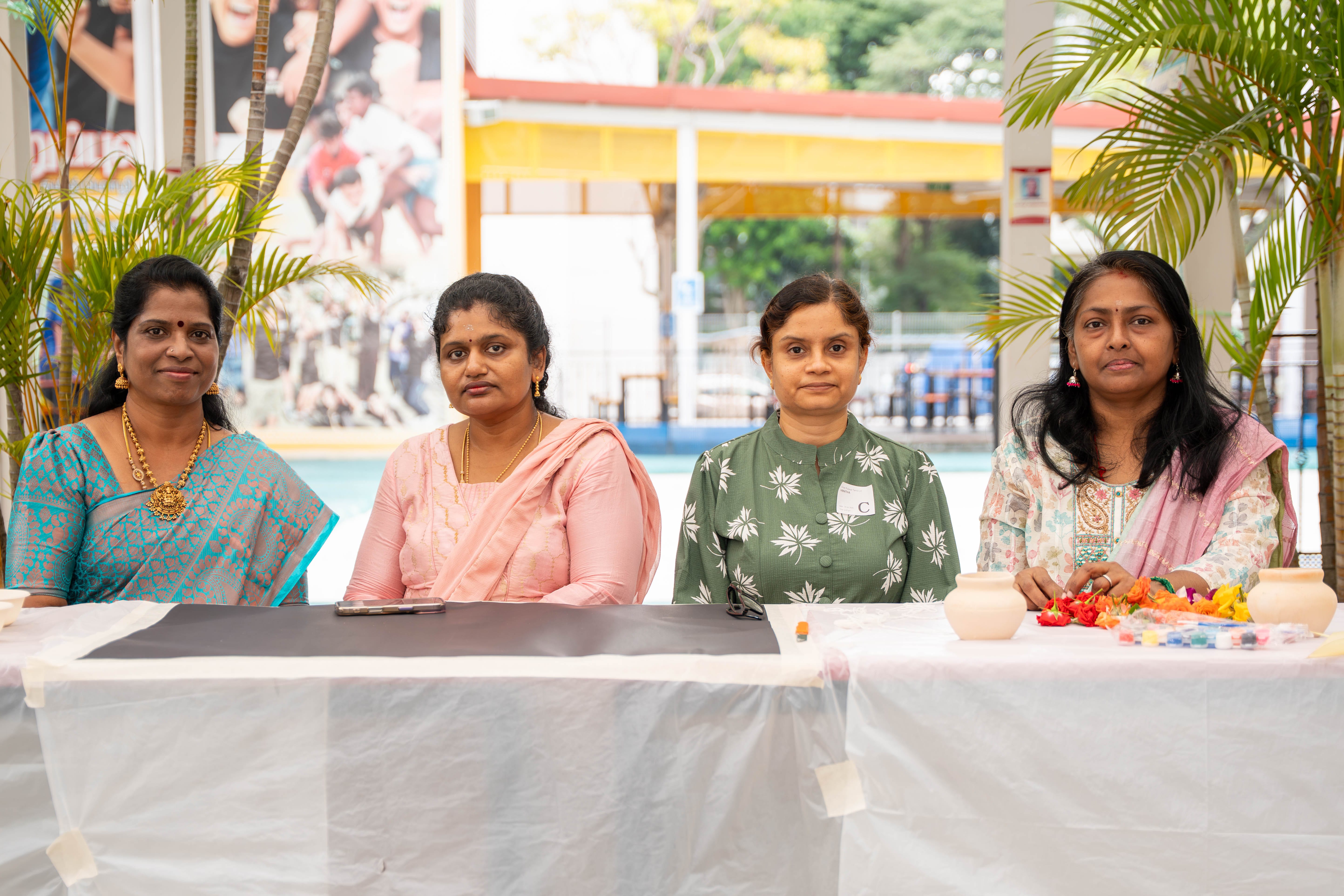 Three parents and a UPTLC librarian seated at an activity table during the Pongal Day 1 Celebration.