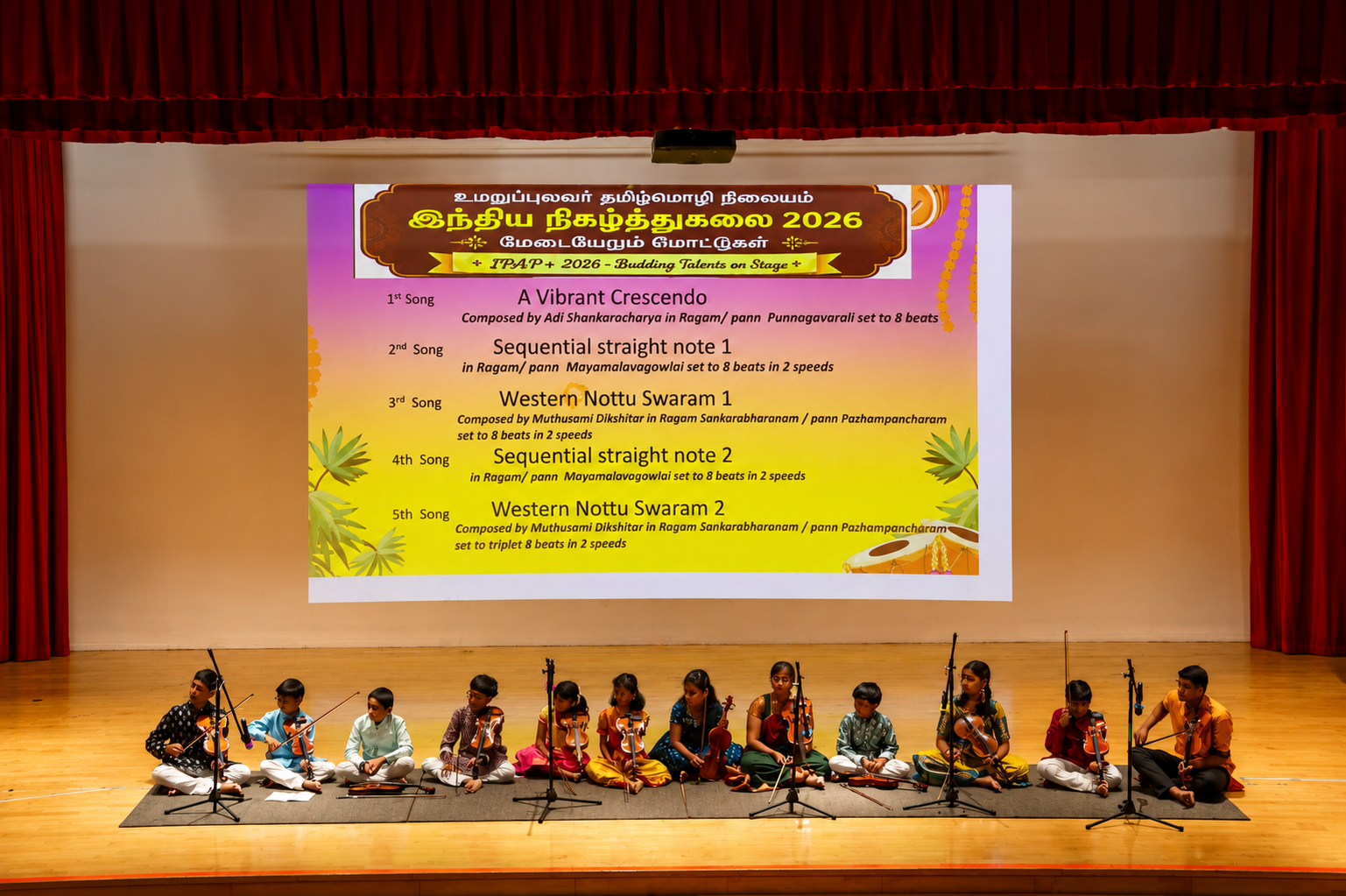 Children seated on stage with violins and microphones under a large projected program list and red curtains