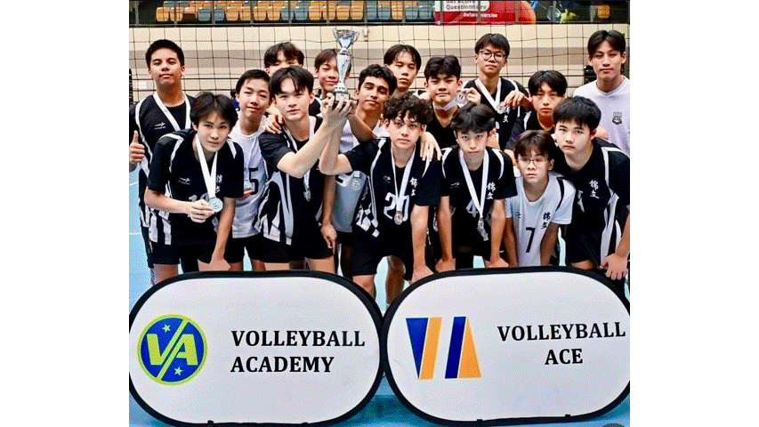 Young male volleyball team in black uniforms posing with a trophy and medals in front of Volleyball Academy and Volleyball Ace banners.